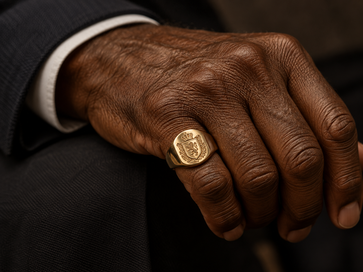 Mão de um senhor negro usando anel sinete dourado